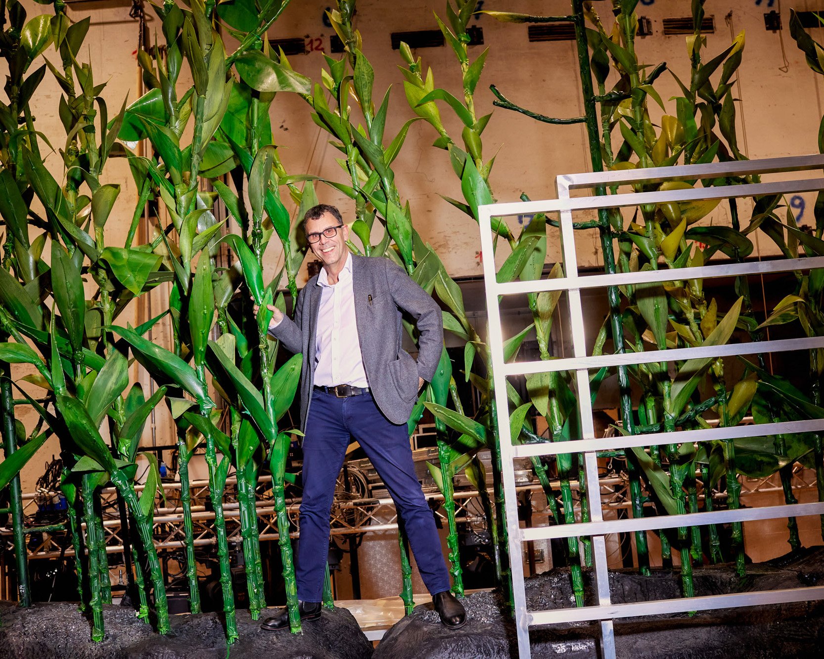 Mann steht vor einer grünen Pflanzen-Kulisse.