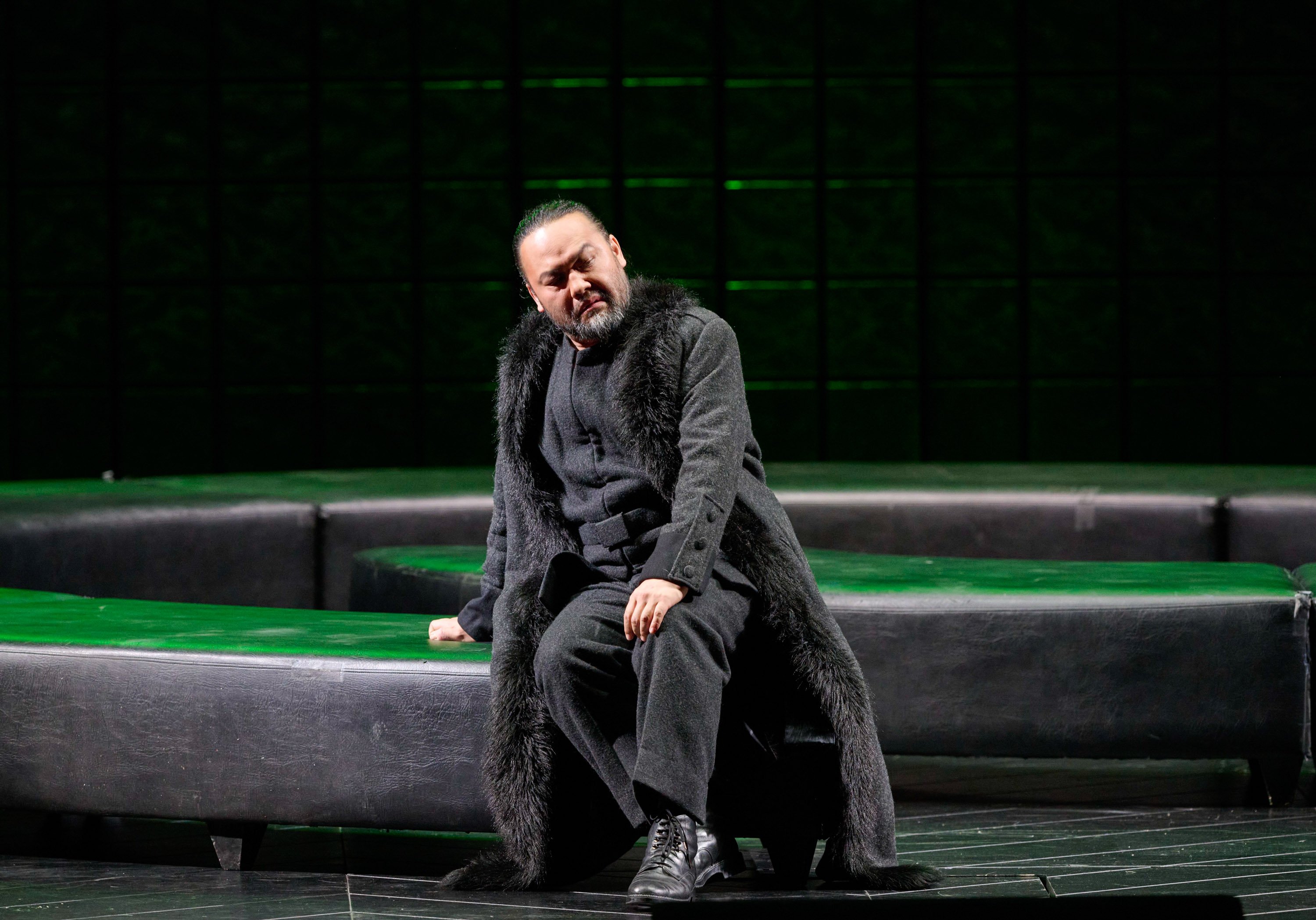 Ein Mann sitzt auf einer Fassade und blickt nach vorne.