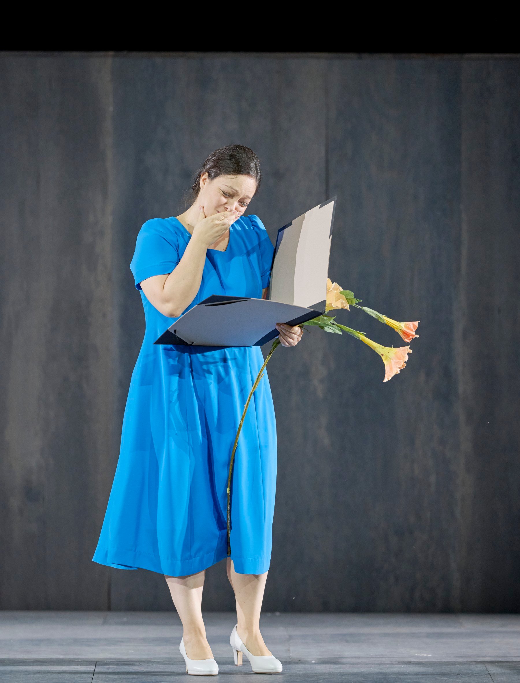 Eine Frau in blauem Kleid liest in einem Buch und wirkt schockiert 