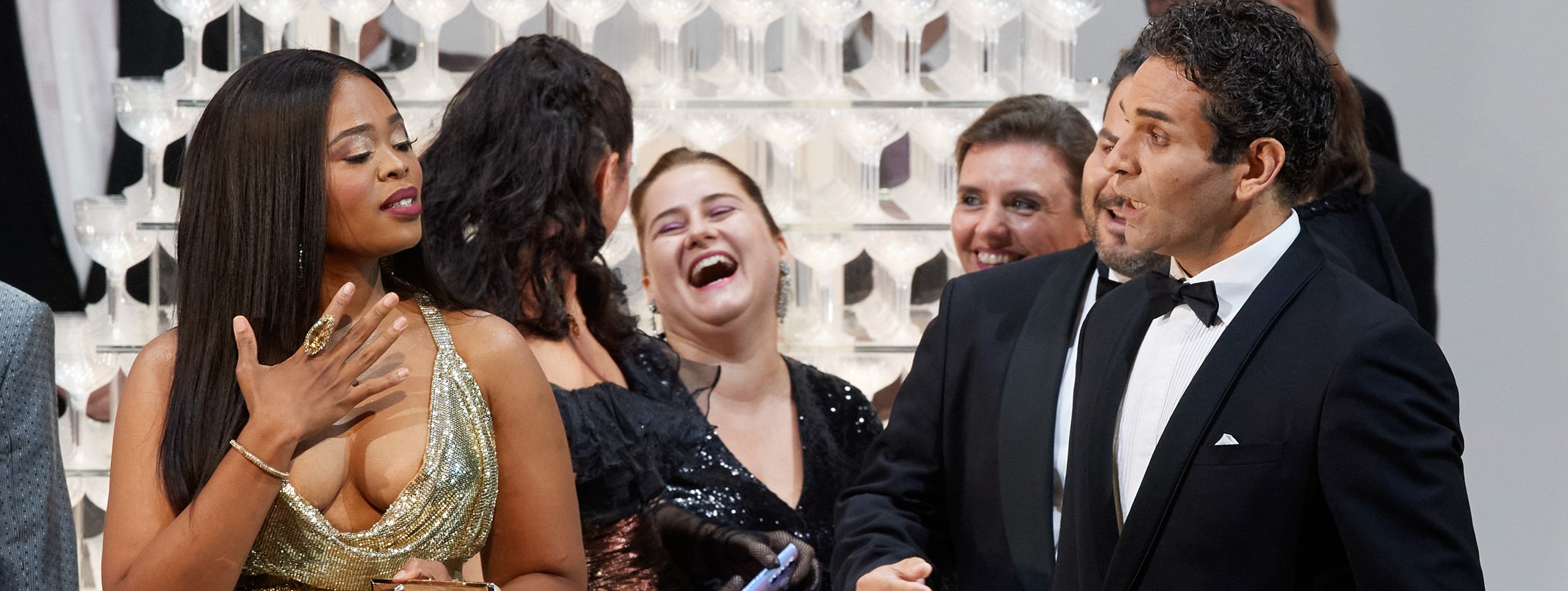 Mehrere elegant gekleidete Personen stehen zusammen und lachen herzlich bei einem festlichen Anlass.