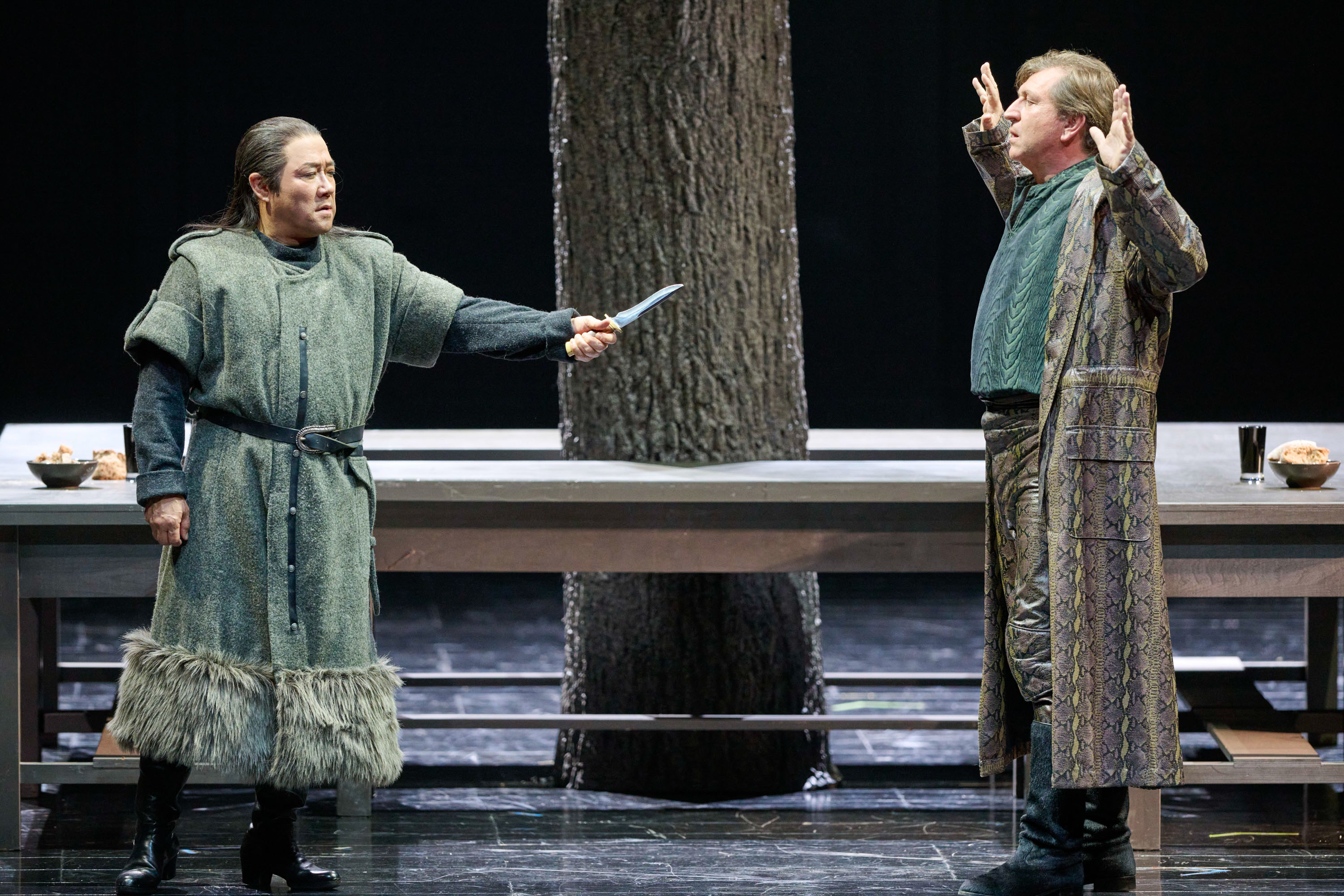 Zwei Menschen in mittelalterlicher Kleidung stehen sich auf einer Bühne gegenüber, einer davon hält ein Messer erhoben.