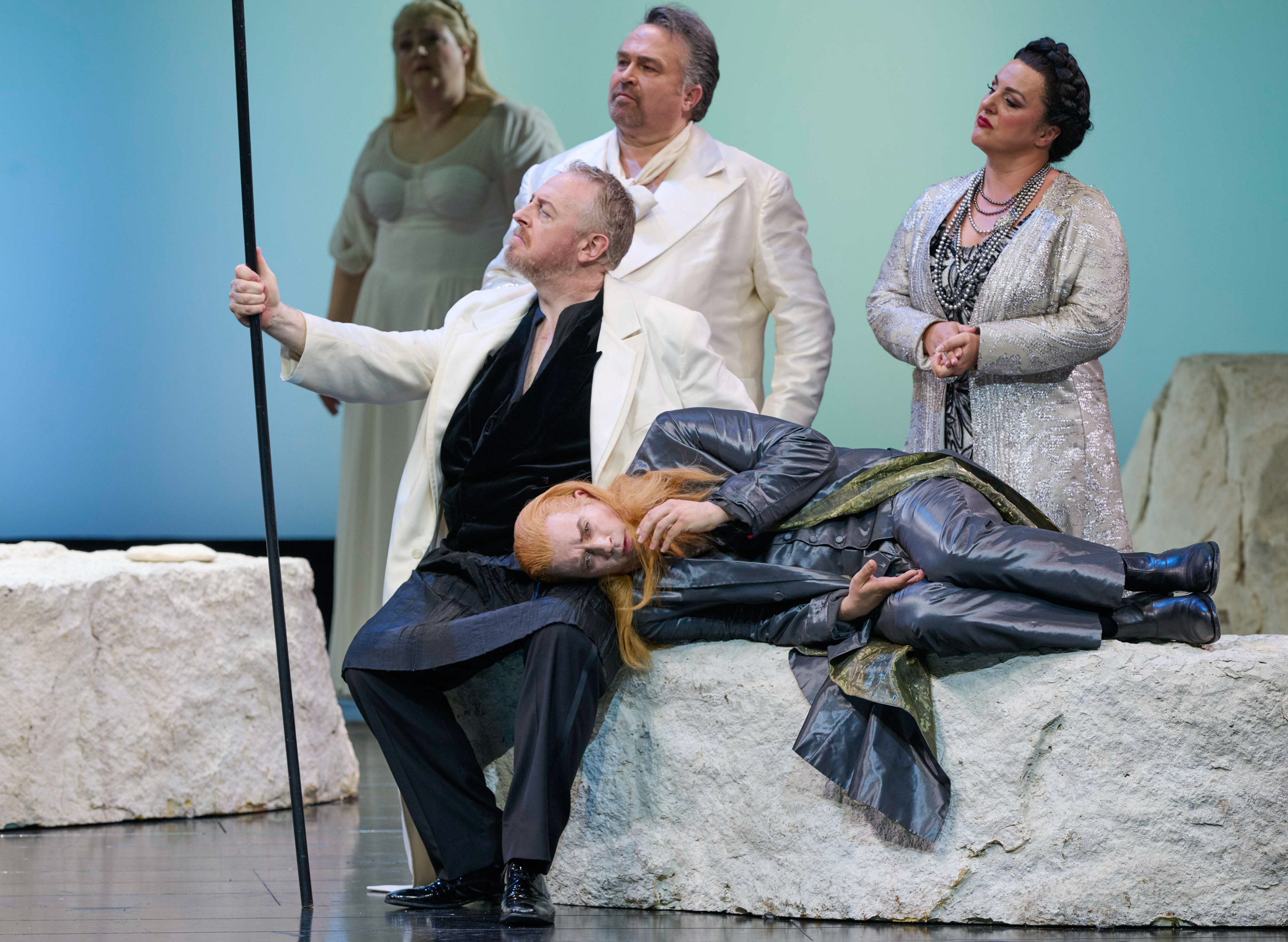 Mehrere Personen in hellenKostümen stehen um eine liegende Frau auf einer Steinbank.