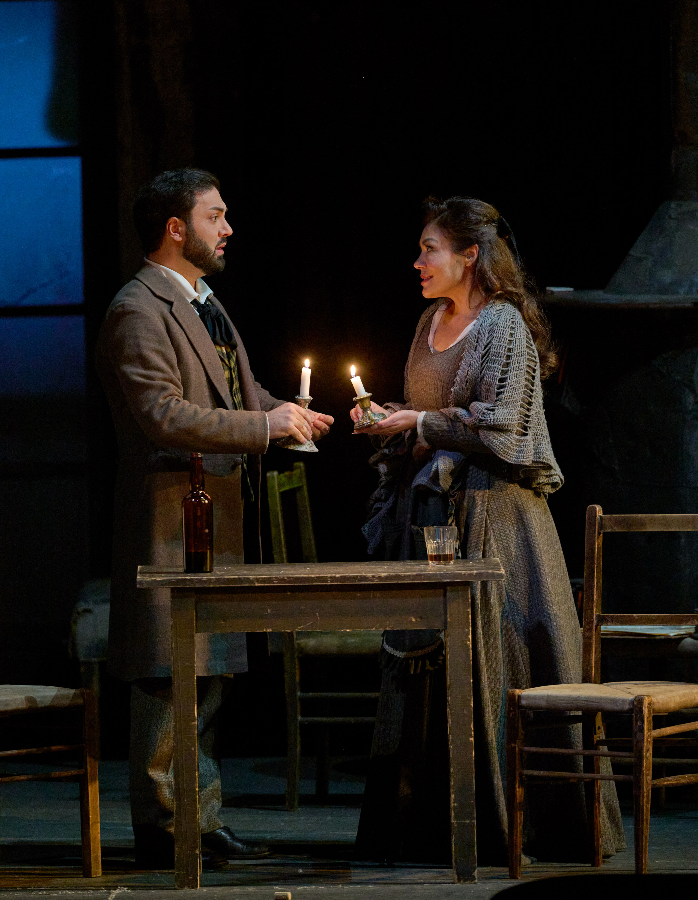 Ein Mann und eine Frau in schlichter historischer Kleidung stehen sich gegenüber und halten jeweils eine brennende Kerze.