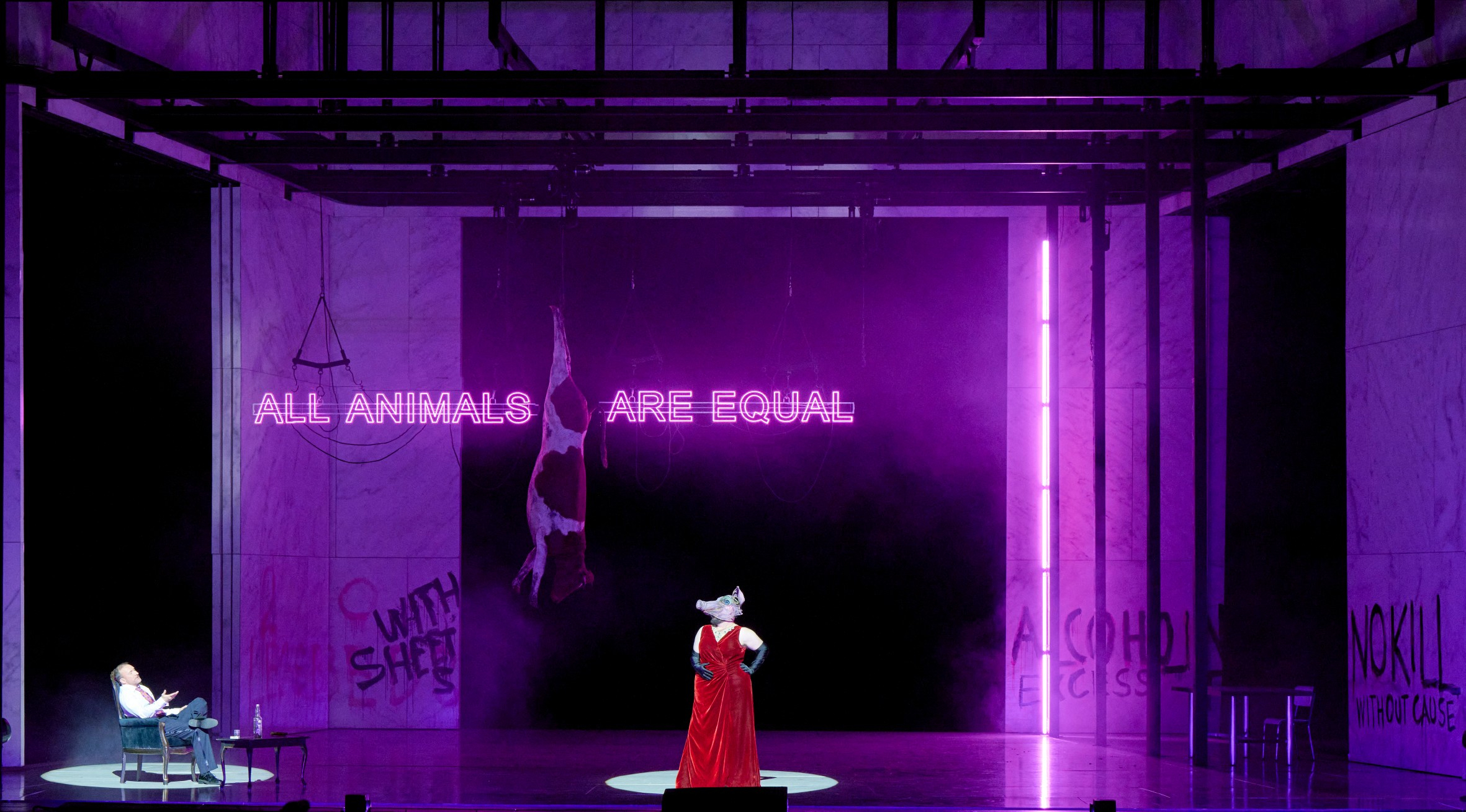 Eine Figur mit Schweinemaske steht in rotem Gewand im Zentrum einer lila beleuchteten Bühne, hinter ihr leuchtet der Satz „ALL ANIMALS ARE EQUAL“.