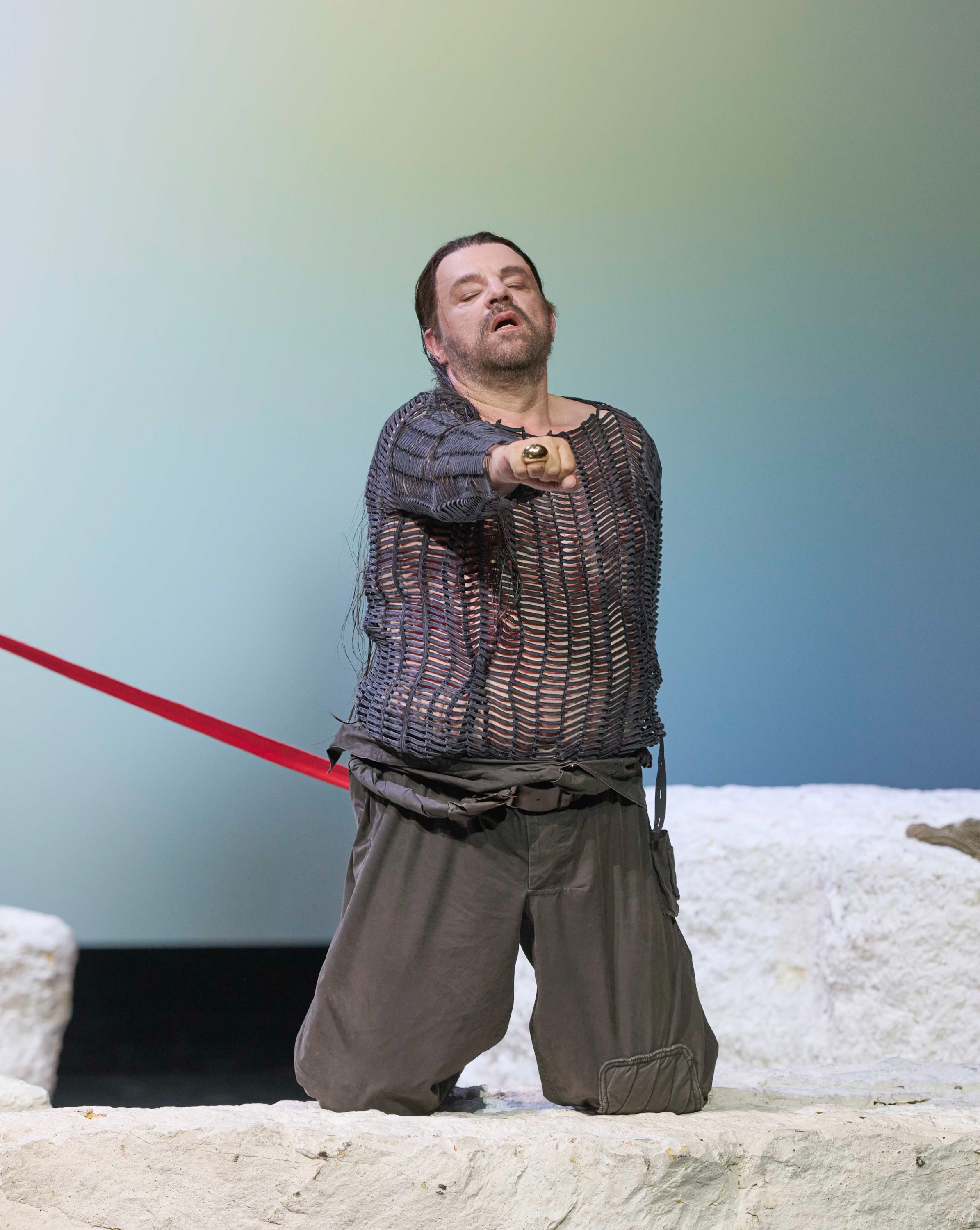 Ein Mann kniet auf einem Felsen und streckt seine Faust nach vorne.