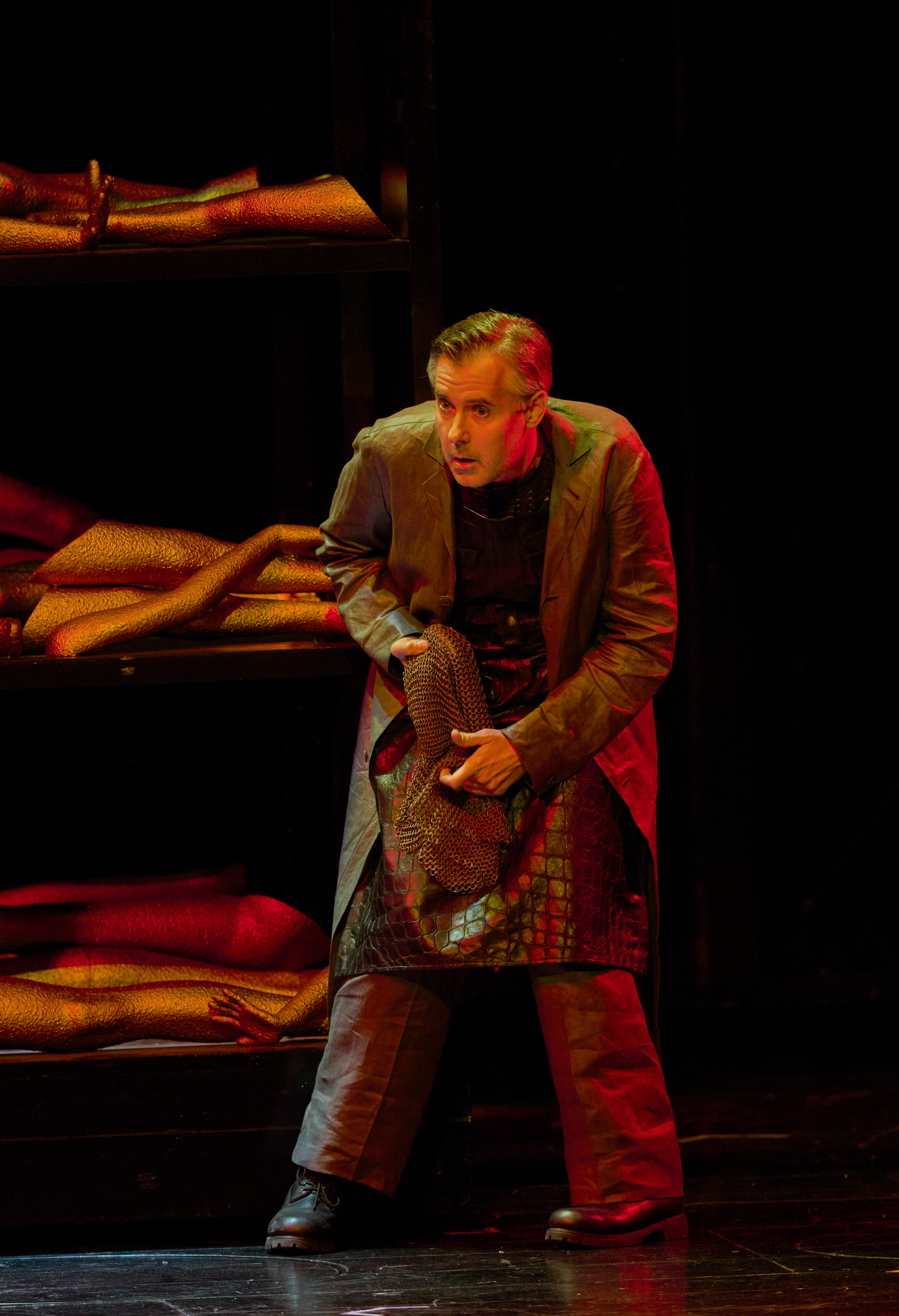 Ein Mann im Mantel duckt sich vor einem dunklen Hintergrund 