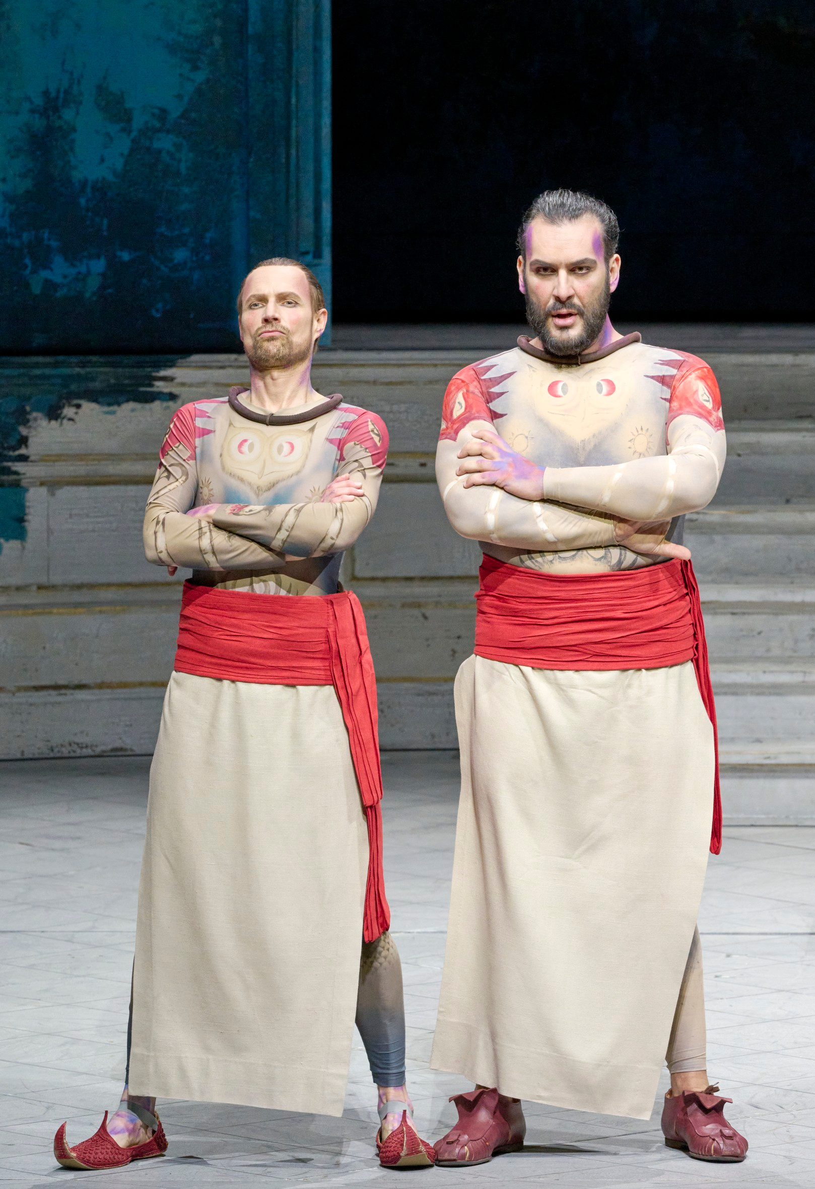 Zwei Männer mit und roten Schärpen stehen mit verschränkten Armen nebeneinander auf einer Bühne.