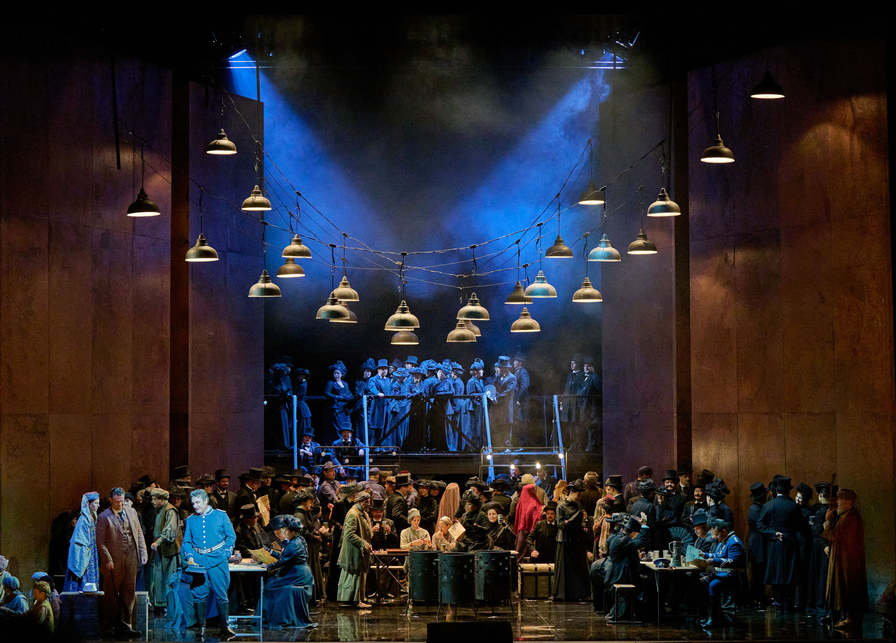 Eine Gruppe Menschen steht auf der Bühne. Über ihnen hängen viele Lampen.